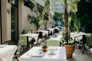a restaurant with white tables and chairs and palm trees at Hotel Crystal in Saarbrücken