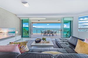 a living room filled with furniture and a large window at Peninsula Airlie Beach in Airlie Beach