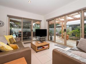a living room with a couch and a tv at Coastal Villa on Beachcomber! in Inverloch