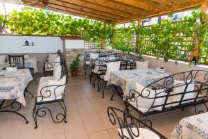 restauracja ze stołami, krzesłami i winoroślą w obiekcie Rodos House w mieście Pomorie