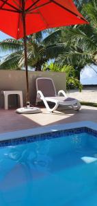 a red umbrella and chair next to a swimming pool at Cote d'Or Footprints in Baie Sainte Anne