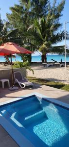 a blue swimming pool next to a beach with an umbrella at Cote d'Or Footprints in Baie Sainte Anne