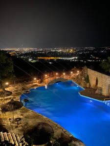 Arolithos Traditional Village Hotel في Tílisos: حمام سباحة كبير مع الماء الأزرق في الليل