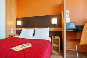 a bedroom with a red bed with a desk and a computer at Première Classe Villejust in Villejust