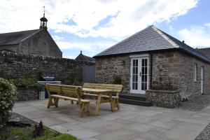 a wooden bench sitting in front of a stone building at Smithy House in Forfar