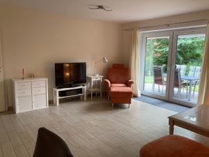 a living room with a television and a chair at Zum Eulennest in Rantrum