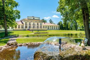 a large building with a pond in front of it at Taujėnų dvaro svečių namai in Towiany