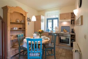 a kitchen with a table and blue chairs in a room at Ferienhaussiedlung Strandperlen Sanddornhof 5d (Typ IV) in Wustrow