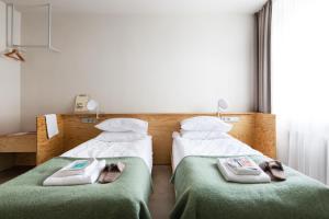 2 Betten in einem Hotelzimmer mit Handtüchern darauf in der Unterkunft Tech Spa Coliving&Coworking Spaces in Druskininkai