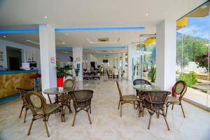 ein Restaurant mit Tischen und Stühlen in einer Lobby in der Unterkunft Hotel Orange in Dhërmi