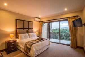 a bedroom with a bed and a balcony with a television at Zimbali Holiday Home - 3 Baluwatu in Durban