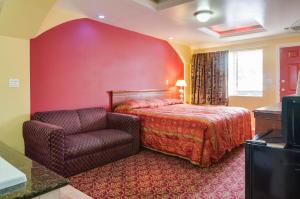 a red bedroom with a bed and a chair at Sky Palm Motel - Orange in Orange
