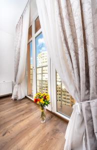 een vaas met bloemen in een kamer met een raam bij Шикарная квартира на Оболони в ЖК Яскравый in Kiev