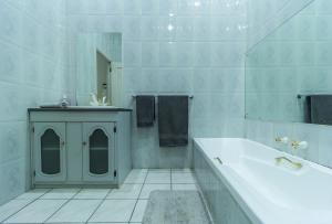 een witte badkamer met een bad en een wastafel bij Charlie's Spot - Norwood in Johannesburg