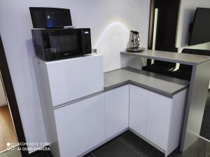 a microwave on top of a white stand with a microwave at Apartman MB in Poprad