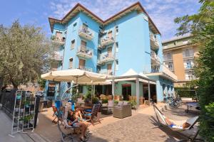 people sitting in chairs in front of a blue building at Art Hotel La Perla in Bellaria-Igea Marina