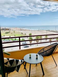 a balcony with a table and chairs and a beach at Costa Caparica surf apartment in Costa da Caparica