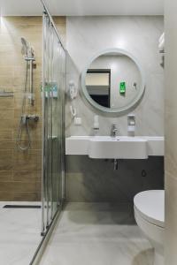 uma casa de banho com um lavatório, um chuveiro e um espelho. em Hotel Buryatia em Ulan-Ude