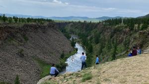 Un groupe de personnes debout sur une colline en train de regarder une rivière dans l'établissement Four Season, à Oulan-Bator