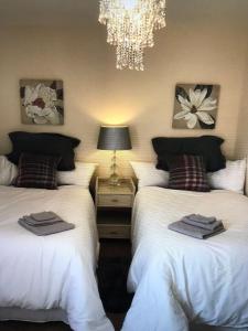 a bedroom with two beds and a chandelier at Lazy Nest is a Lazy comfortable Nest to laze in Oakham
