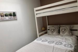 um quarto com um beliche com lençóis brancos e almofadas em Maison lumineuse 3 chambres bordeaux sud em Pont-de-la-Maye