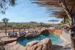a swimming pool with lounge chairs and a large rock at Jock Safari Lodge in Skukuza