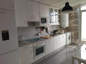 una cocina blanca con armarios blancos y fregadero en Residencial Mondariz Balneario 424, en Mondariz-Balneario