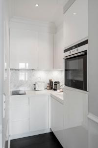 a white kitchen with white cabinets and a microwave at Villa Palazzo in Tegernsee