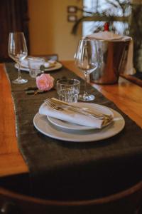 a table with plates and napkins and wine glasses at La Foresteria di Villa Piazzo in Pettinengo