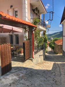 una casa con patio con tavolo e ombrellone di Guesthouse Monopati - Ξενώνας Μονοπάτι a Lechovo