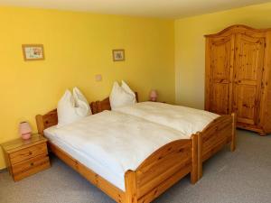 um quarto com uma grande cama de madeira com lençóis brancos em FeWo25-Zimmer-am-Bodensee em Markdorf