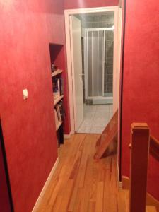 un pasillo con una pared roja y una puerta y un pasillo con suelo de madera en Maison Guigon en Saint-Désirat