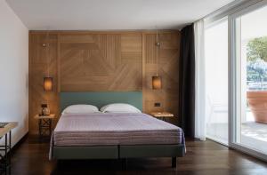 Aris Apartments & Sky Pool - TonelliHotels في ريفا ديل غاردا: غرفة نوم بسرير مع جدار خشبي