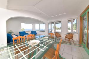 uma sala de estar com uma mesa de vidro e cadeiras em Villa Stefania em Ischia