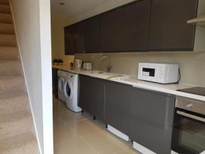 a kitchen with a washing machine and a microwave at Modern split level flat in Croydon (south) London in London