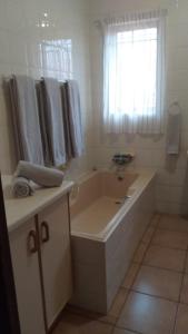 Un baño con bañera, lavabo y ventana. en Hooked on 6 Fish Eagles, en St Lucia
