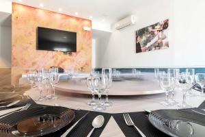 uma mesa com copos de vinho e uma televisão na parede em Mini Hotel Wf2 Caltagirone em Caltagirone