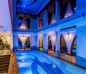 a pool in a hotel with blue lighting and stairs at Szklarska Poręba Apartament MARILYN MONROE 301 in Szklarska Poręba