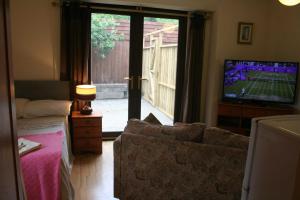 a living room with a couch and a television with a tennis game at The Nook - Farm Park Stay with Hot Tub & Dome in Swansea