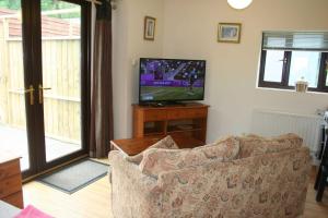 a living room with a couch and a flat screen tv at The Nook - Farm Park Stay with Hot Tub & Dome in Swansea +18 photos