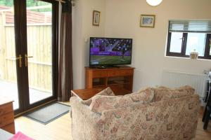 a living room with a couch and a flat screen tv at The Nook - Farm Park Stay with Hot Tub & Dome in Swansea