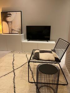 un soggiorno con sedia e TV a schermo piatto di 3 Room Luxury Design Apartment a Gand