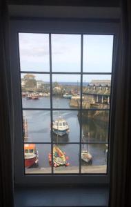 een raam met uitzicht op een haven met boten in het water bij The Wheel House in Mevagissey