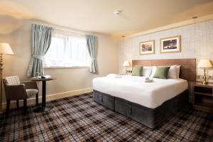um quarto de hotel com uma cama grande e uma cadeira em The Black Swan - The Inn Collection Group em Helmsley