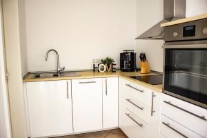 uma cozinha com armários brancos e um lavatório em Ferienwohnung Alte Burg Koblenz em Koblenz