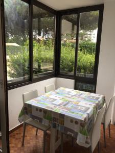 una mesa y sillas en una habitación con ventanas en Studio Cap Sud Capbreton proche plage en Capbreton