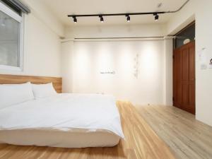 東港的住宿－艾睏khùn行旅，卧室配有白色的床,铺有木地板