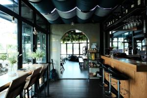 a restaurant with a bar with chairs and windows at Wayha Hostel Don Mueang Airport in Bangkok
