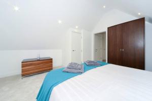 a bedroom with a white bed with a wooden cabinet at Seaview apartment in Southbourne