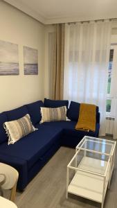 - un canapé bleu dans le salon avec une table en verre dans l'établissement Apartamento Buenavista, à Oviedo